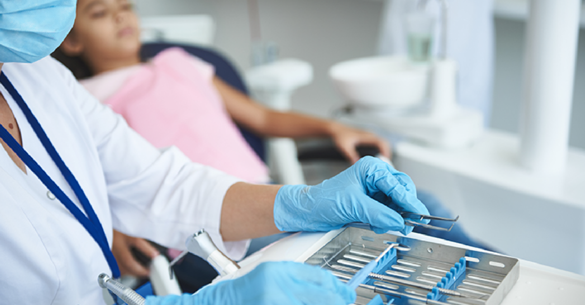 Headline picture from Health Affairs article depicting a medical professional in mask & gloves typing