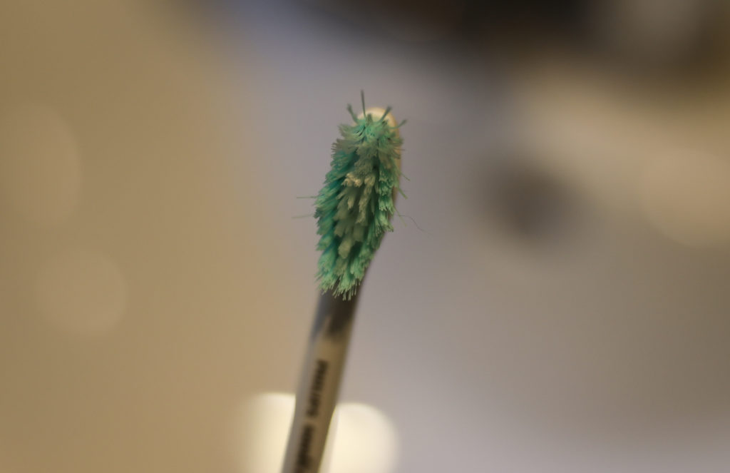 A picture of a frayed toothbrush, with bristles flattened and sticking out in different directions